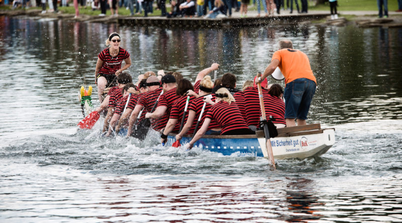 Das Drachenboot setzt sich in Bewegung. Der Steuermann und der Trommler schreit und feuern die Mannschaft an.