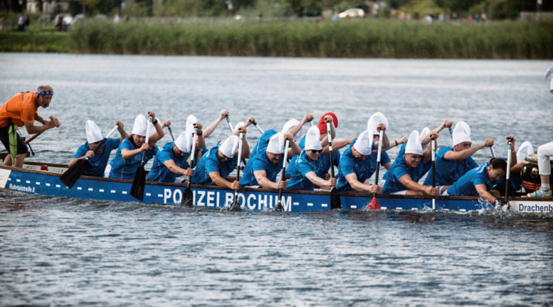 Eine Drachenbootmannschaft mit Schlupfmützen und blauen T-Shirts