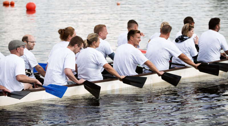 Konzentration von dem Start. Die Drachenbootmannschaft hält die Paddel hoch.